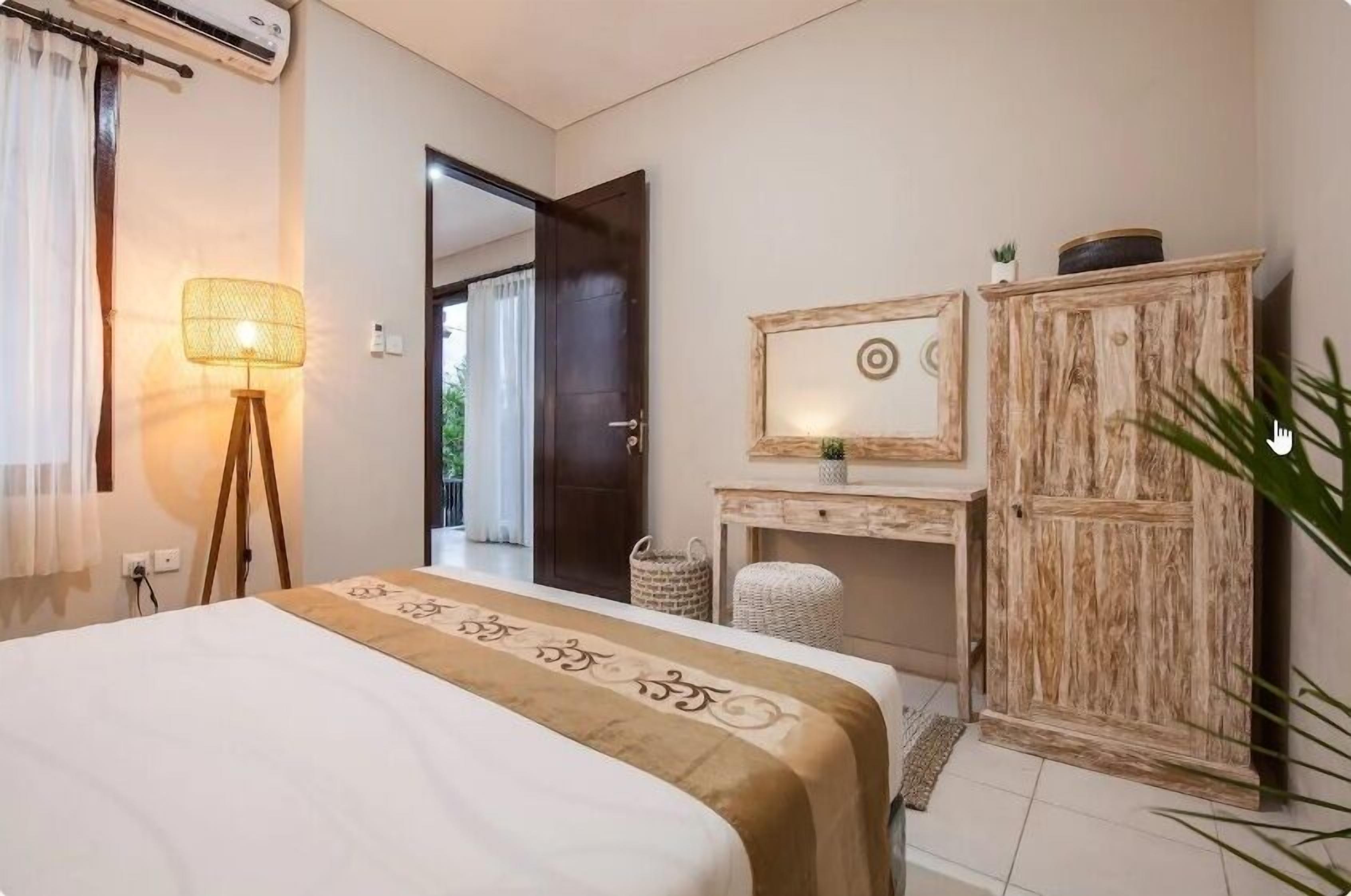 Un dormitorio con cama, lámpara de noche, armario y espejo.