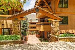 Un lodge in legno con ingresso in pietra, diverse finestre e un portico coperto.