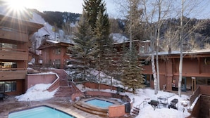 A resort with a swimming pool, outdoor seating, and a snow-covered landscape.