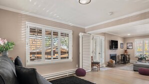 A spacious living room with a large window, a fireplace, and a television.
