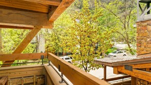 A wooden balcony with a view of a tree-lined street and parked cars.