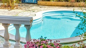 En swimmingpool med stendæk og en hvid gelænder.