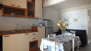 A compact kitchen with a sink, cabinets, and a dining area with a table and chairs.