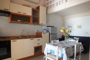 Une cuisine compacte avec des meubles en bois, un four encastré, un évier et un coin repas comprenant une table et des chaises.