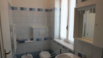 A bathroom with a toilet, bidet, and bathtub.