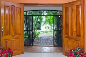 Step outside to a serene outdoor space with lush greenery and a paved walkway.