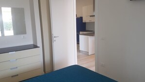 Un dormitorio con cama, armario y puerta que da a una cocina.
