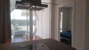 Una cocina moderna con zona de comedor de vidrio, estufa integrada y vistas al exterior.