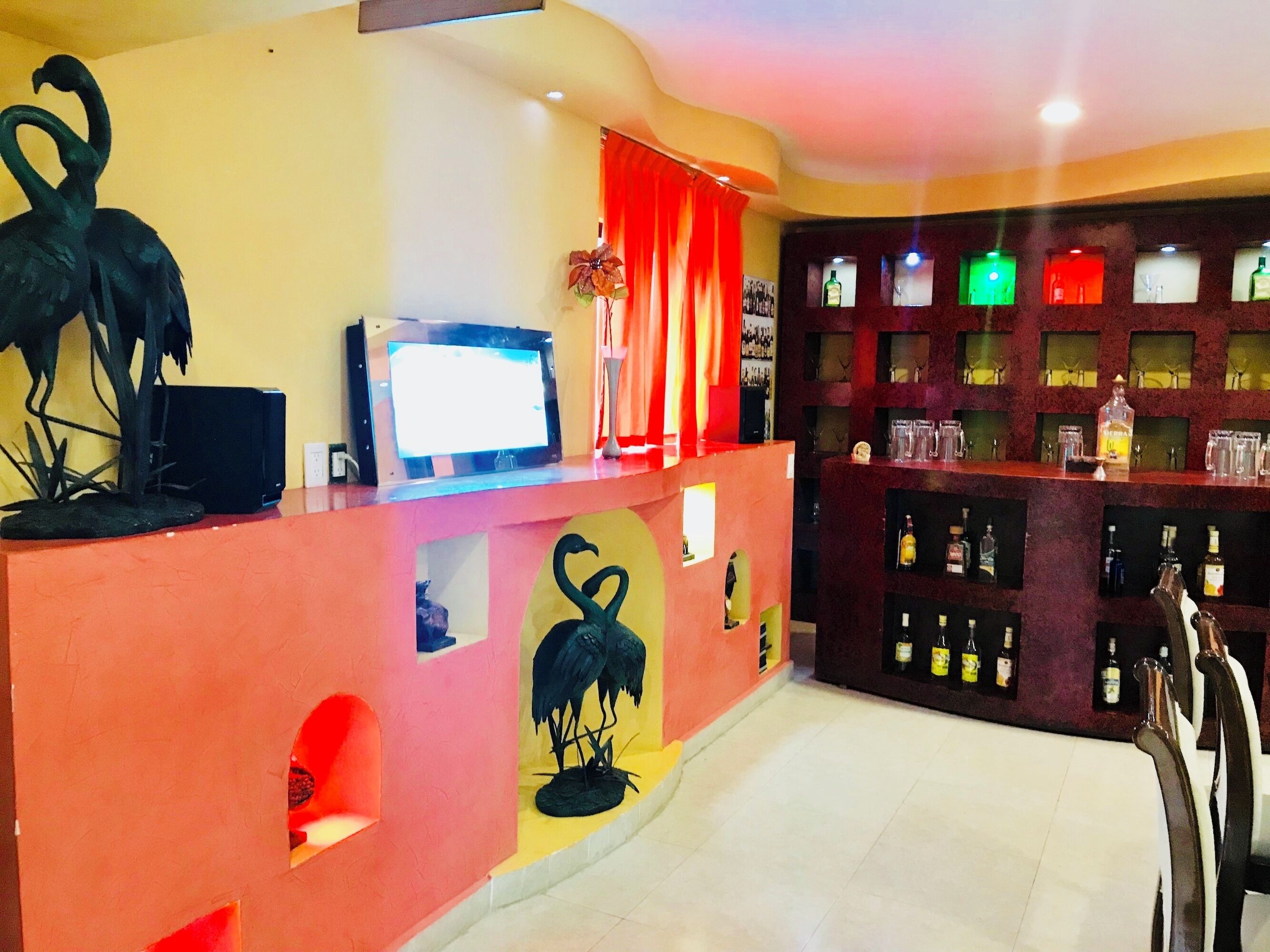 A bar area with a counter, shelves of liquor bottles, and decorative swan sculptures.