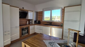Een moderne keuken met witte kastjes, een houten aanrecht, een ingebouwde oven en een raam met uitzicht.