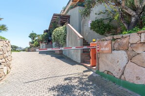 Una entrada con puerta de reja, un muro de piedra, una escalera y un letrero que dice 'Astodeli'.