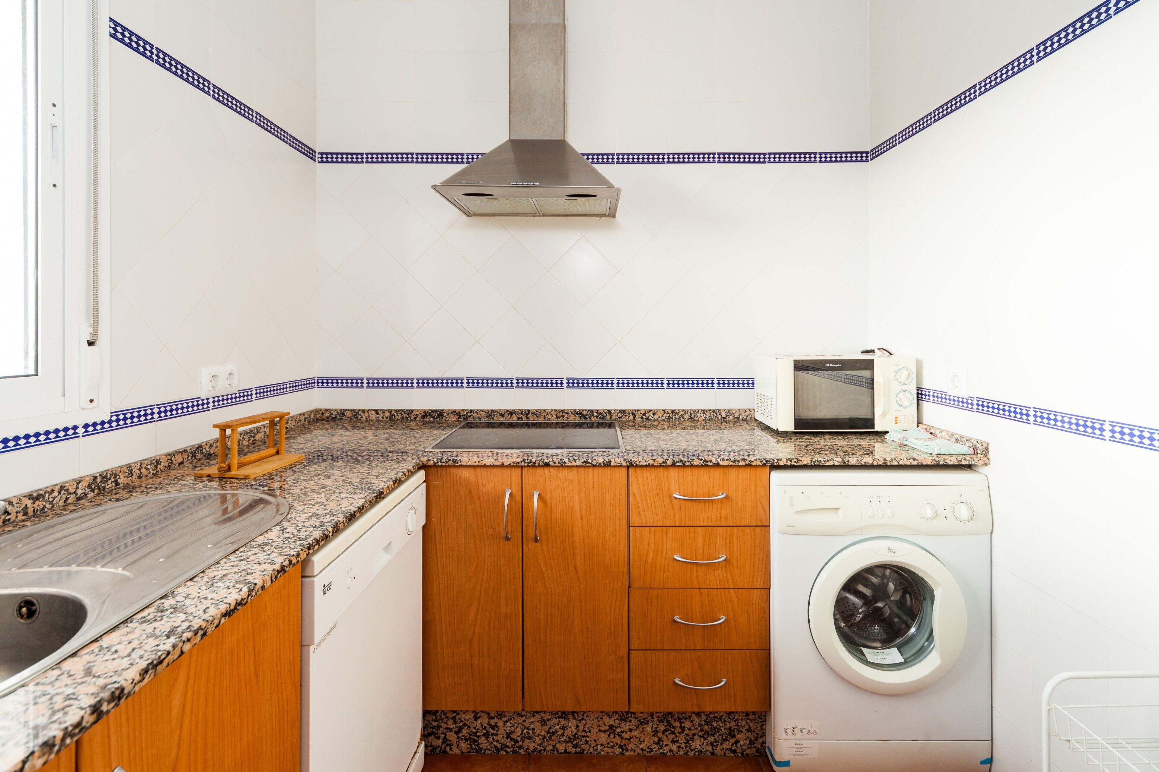 A compact kitchen with a sink, microwave, and washing machine.