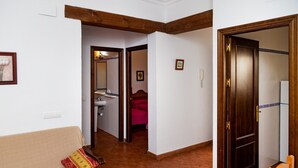 A living room with a sofa, a wooden door, and a hallway leading to a bathroom.