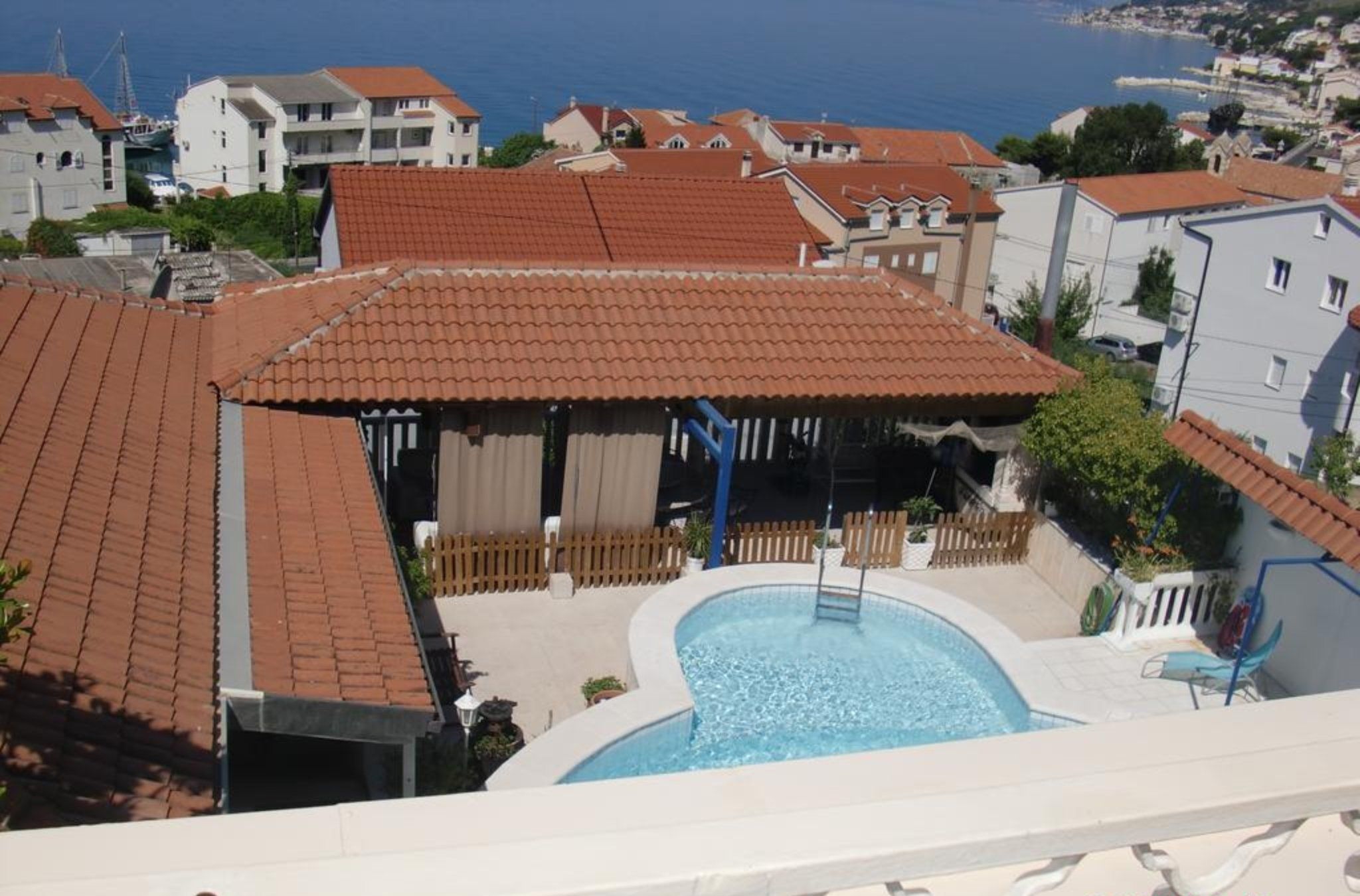 A residential area with a swimming pool surrounded by houses with red-tiled roofs.