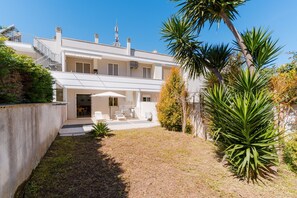 Una casa a due piani con un patio, posti a sedere all'aperto e una scala.