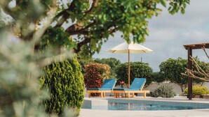 A pool area with lounge chairs and an umbrella, surrounded by greenery and a pergola. - Pefki Beach Front Villa (Rhodes)