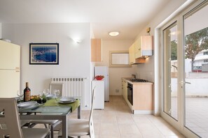 A compact kitchen with a dining area, a refrigerator, a stove, and a window with a view.