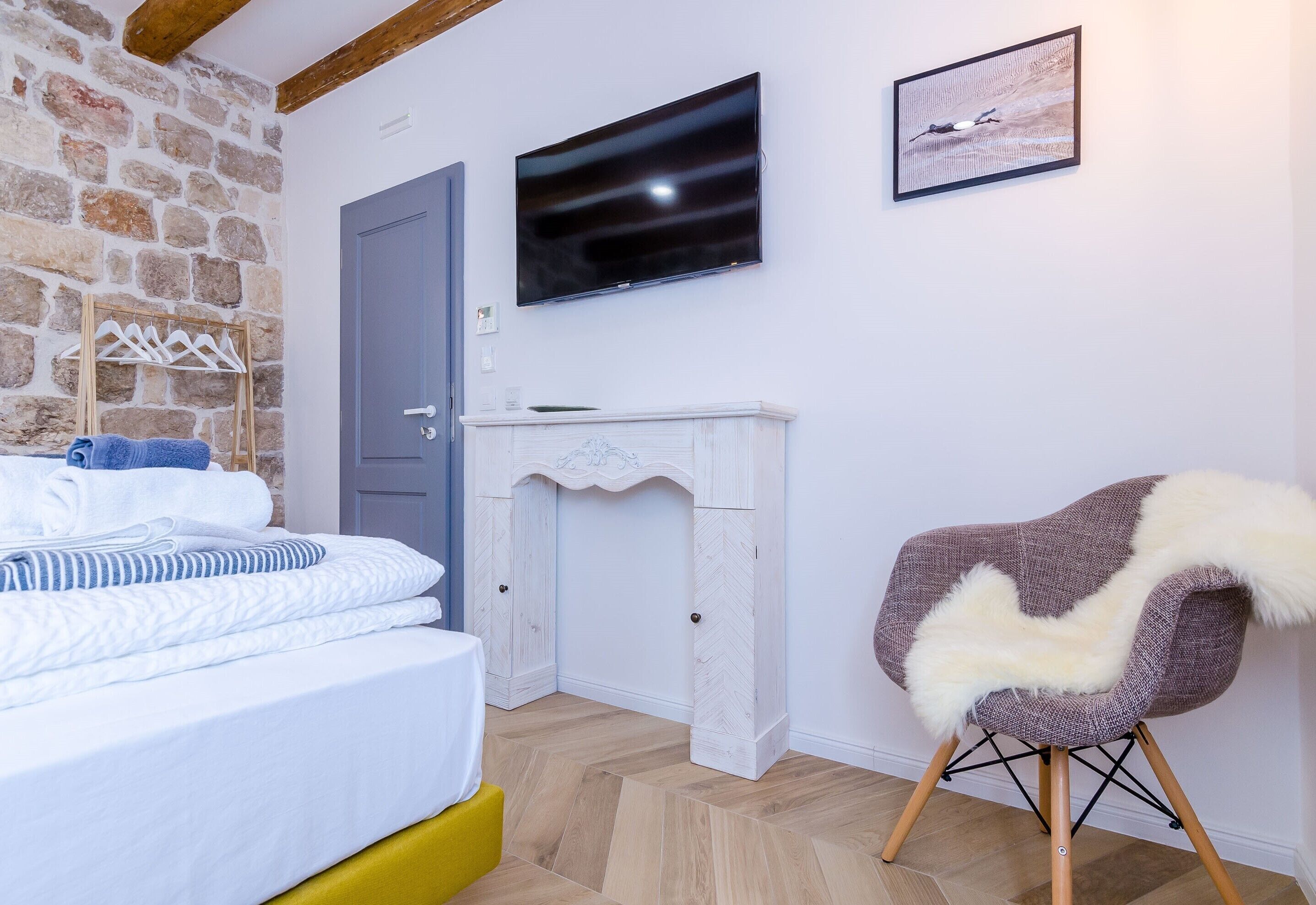 A bedroom with a bed, a television, a fireplace, and a chair.
