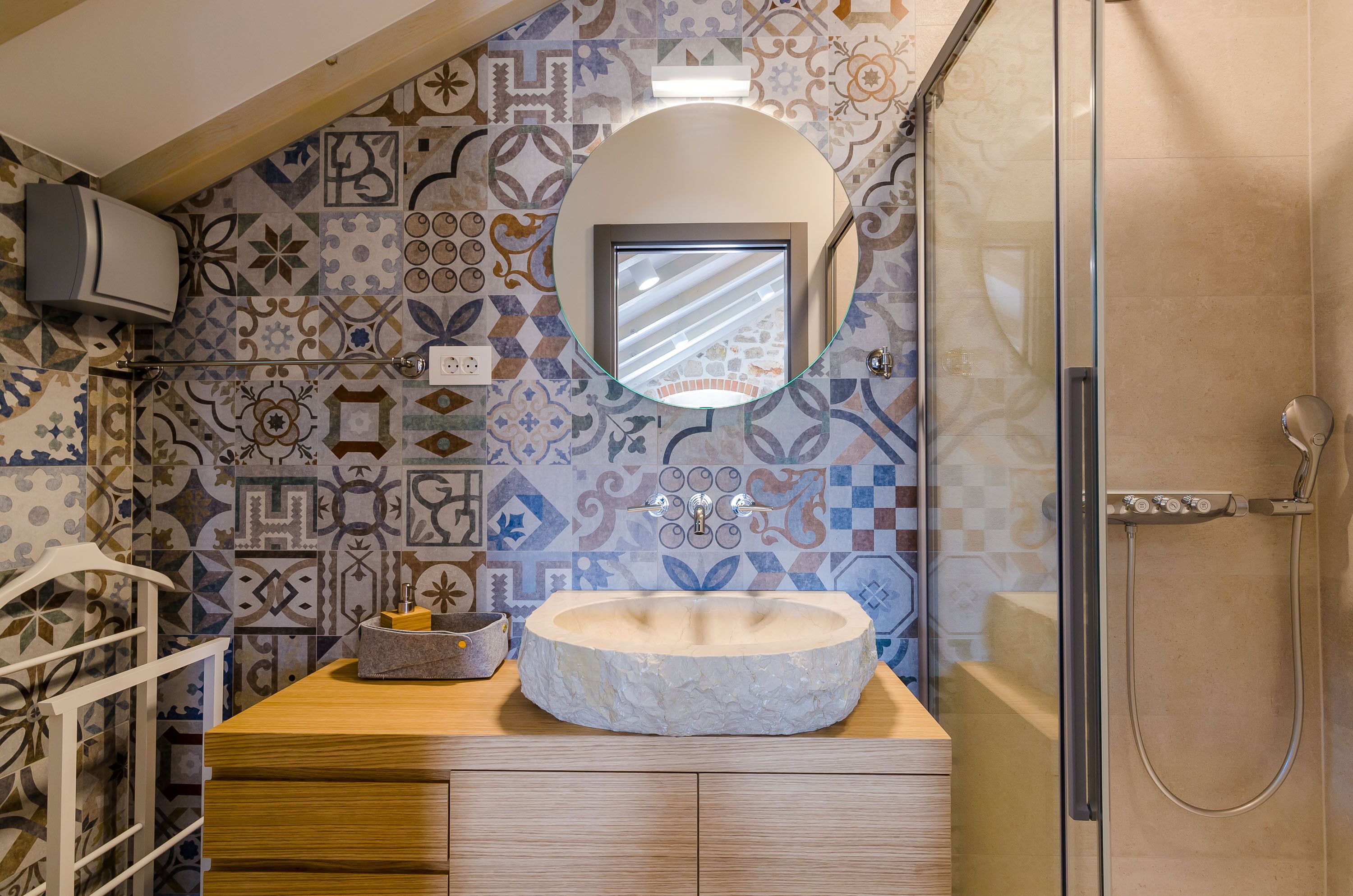 A bathroom with a stone sink, a mirror, and a shower.