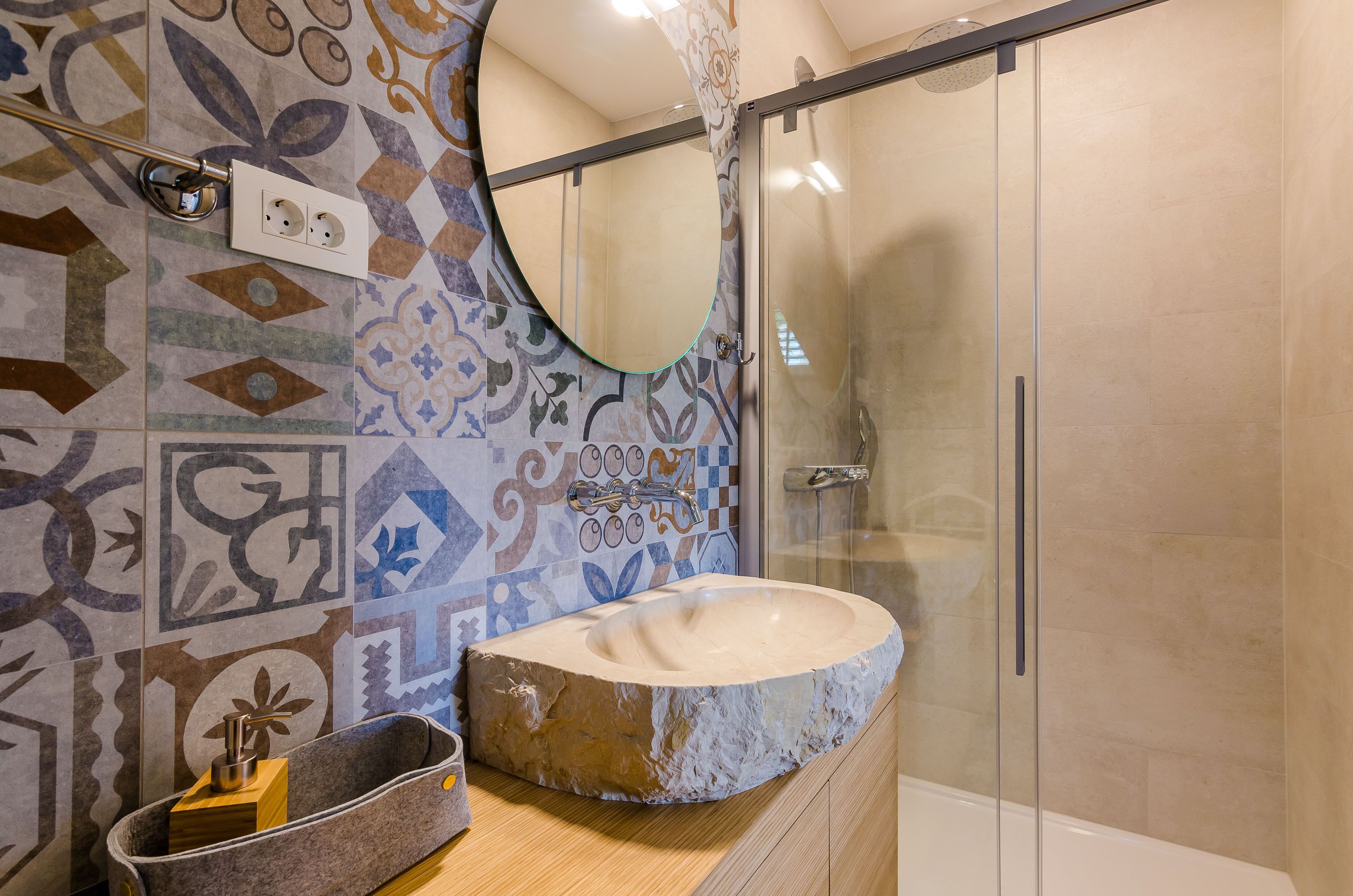 Une salle de bain avec un lavabo en pierre, un miroir et des carreaux décorés.