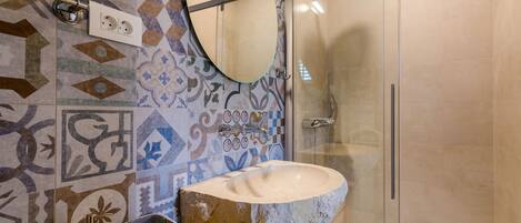 Une salle de bain avec un lavabo en pierre, un miroir et des carreaux décorés.