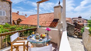 Un balcón con una mesa lista para el desayuno, con vista a un paisaje urbano de tejados de terracota y edificios históricos.