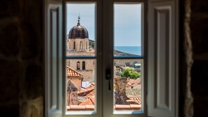 Vista a través de una ventana que muestra un muro de piedra, un edificio con cúpula y una masa de agua.