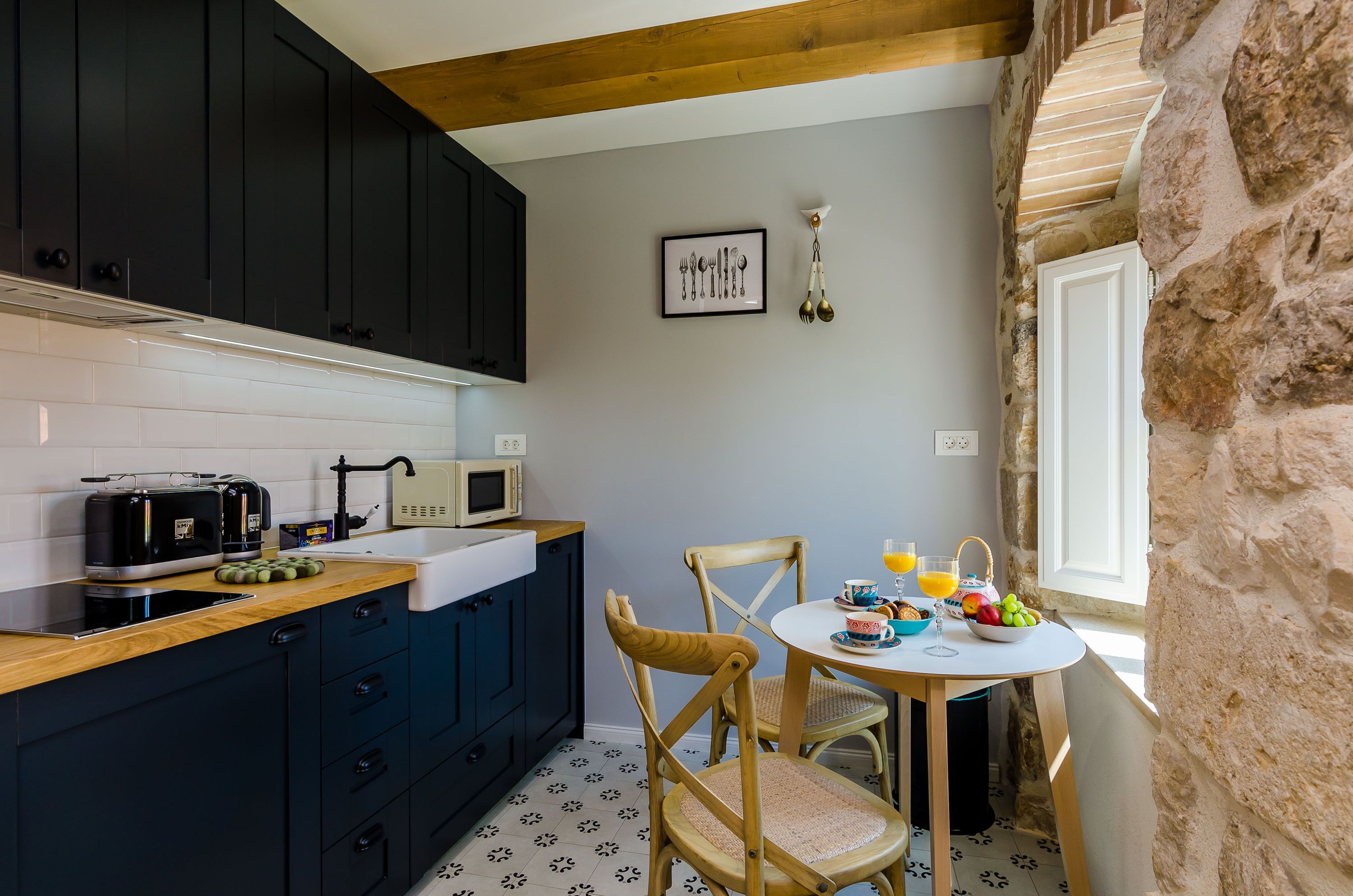 Una cocina con armarios oscuros, una encimera de madera, un microondas y una zona de comedor con una mesa puesta para dos.