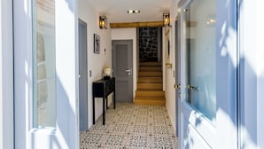 Un pasillo con piso estampado, una escalera de madera y una pared de piedra.
