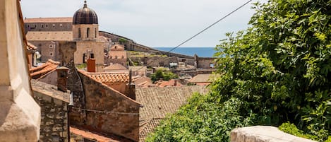 Un paisaje urbano histórico con edificios de piedra, una estructura cúpula destacada y vista al mar.