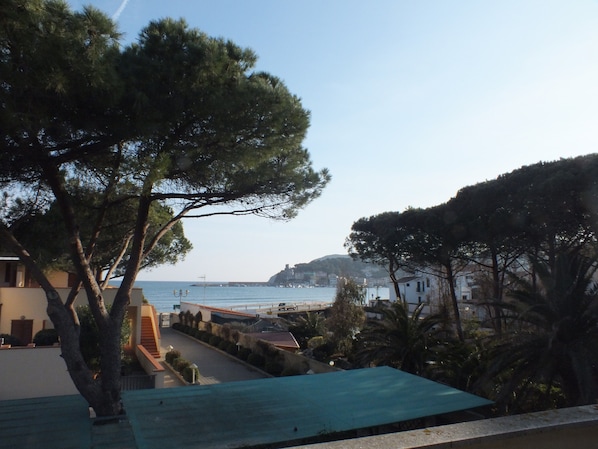A coastal view with a building, trees, and a clear sky.