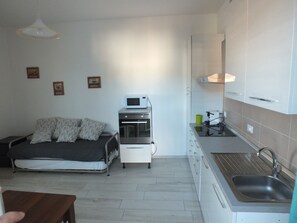 Een ruimtelijk ingedeeld verblijf met een kitchenette, een bed en een klein eethoekje.