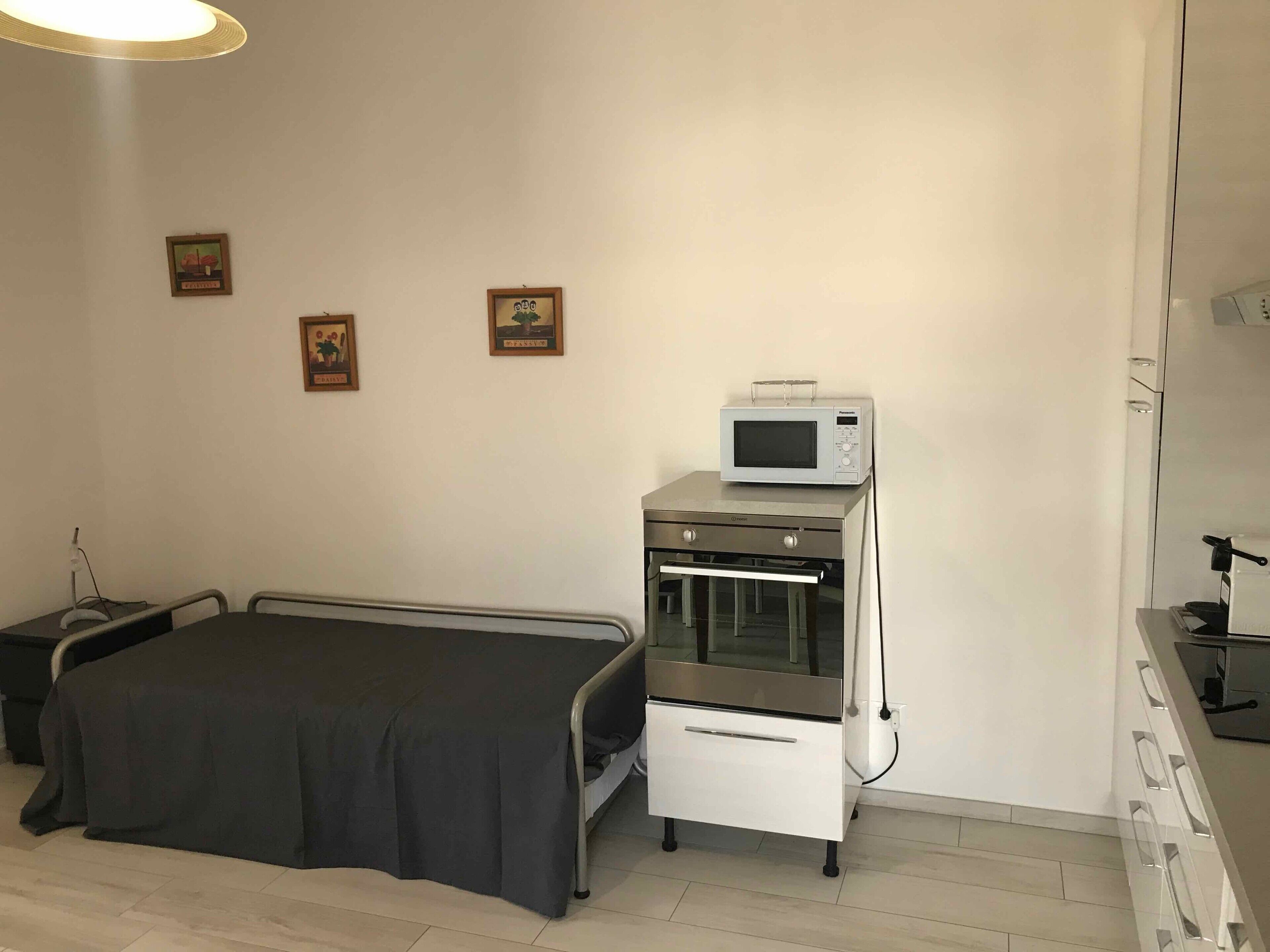 Une chambre avec un lit, un four à micro-ondes, un four et une petite table.