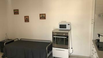 Une chambre avec un lit, un four à micro-ondes, un four et une petite table.
