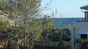 Vista costera con un edificio, árboles y el mar.