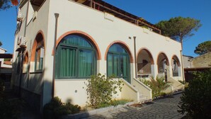 Un edificio con ventanas arqueadas, una escalera y una entrada empavedada.