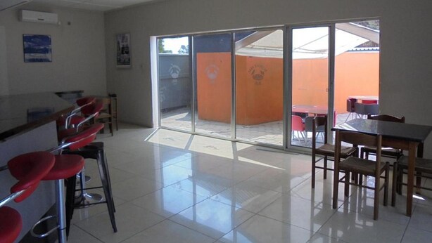 A spacious room with a large sliding glass door leading to an outdoor area with tables and chairs. - Belden s Nest Lodge (Ndola)