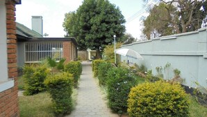A pathway leading to a building with a brick facade and a large tree in the background. - Belden s Nest Lodge (Ndola)