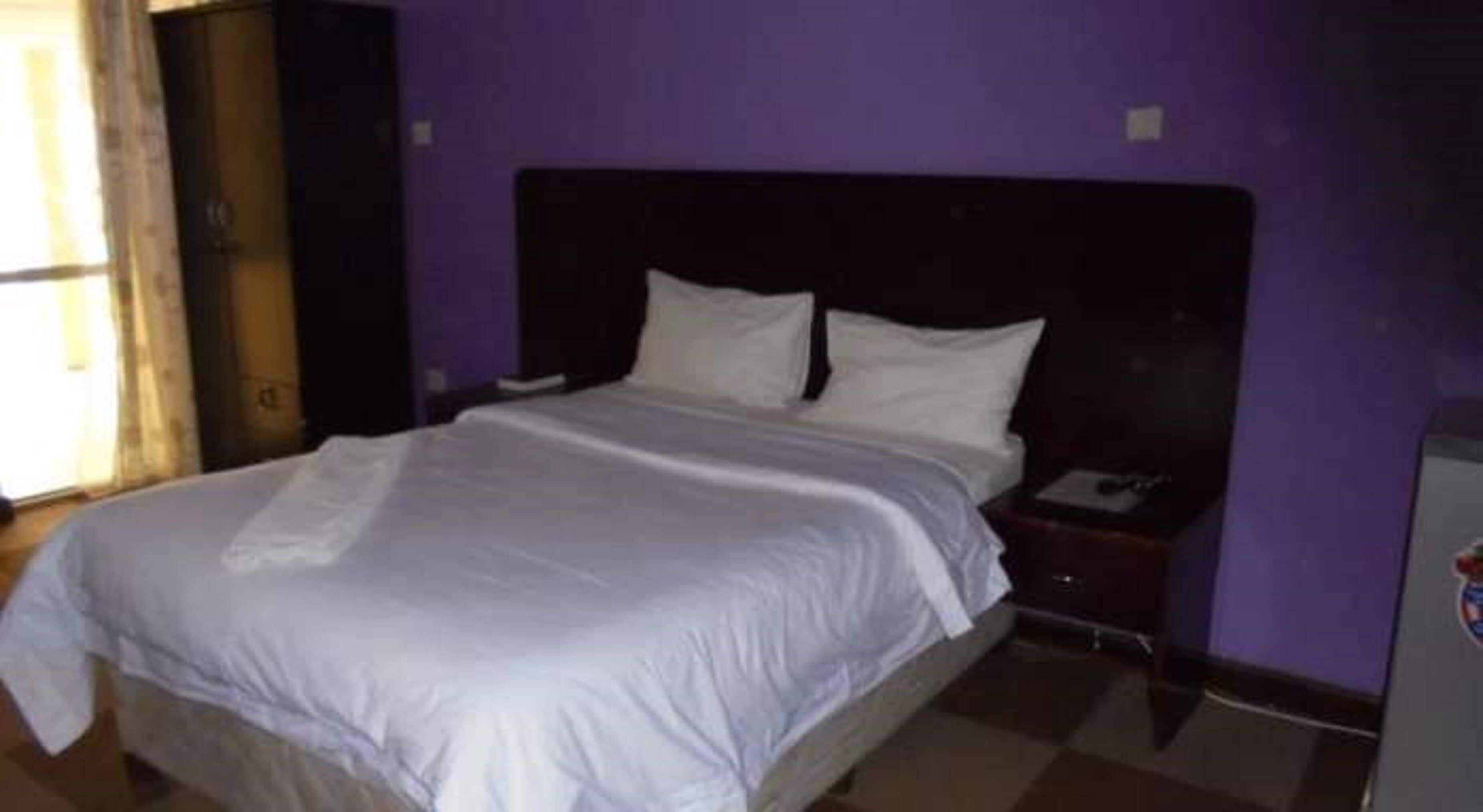 A room with a bed, a nightstand, and a wall-mounted telephone.