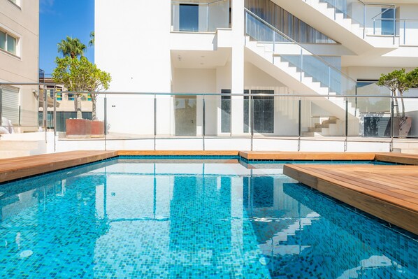 A modern building with a swimming pool, glass railings, and a staircase.