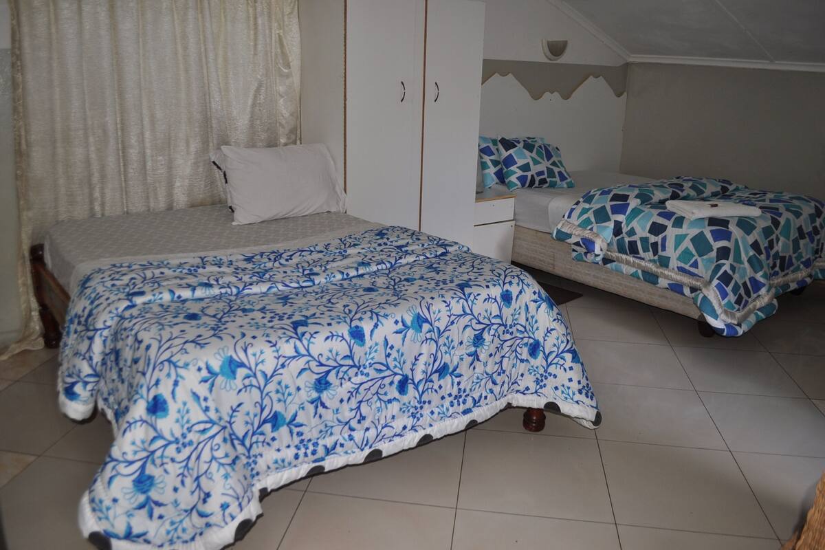A bedroom with two beds, a wardrobe, and a window with curtains.