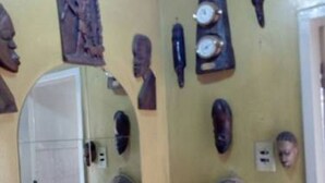 Una habitación con un espejo grande, varias esculturas en la pared y un suelo de baldosas.