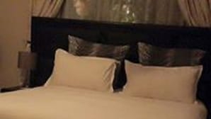 Una cama con cabecera oscura y ropa de cama blanca.