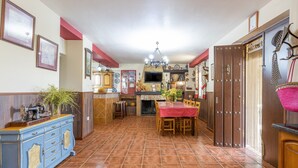 A spacious kitchen with a dining area, wooden cabinets, a chandelier, and a tiled floor. - Holiday Home "Cortijo Rural Puerto Nuevo" with Pool, Garden, Terrace & Wi-Fi (Málaga)