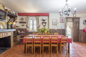 Un comedor con una mesa dispuesta para seis personas, sillas de madera, una araña y techo rojo.