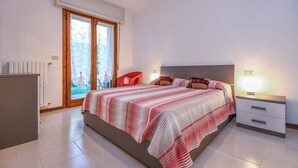 A bedroom with a bed, bedside tables, a radiator, and a window with curtains. - Great Location with Charming Patio - Prato Verde - Girasole (San Felice del Benaco)