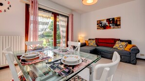 A dining area with a glass table, chairs, and a red pendant light. - Great Location with Charming Patio - Prato Verde - Girasole (San Felice del Benaco)