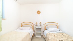Una habitación pequeña y limpia con dos camas individuales, una mesita de noche con lámpara y un adorno en la pared.