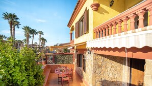 Un patio con una mesa, sillas, un muro de piedra y una puerta.