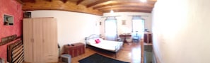 A bedroom with a bed, a wardrobe, a desk, and a chair.